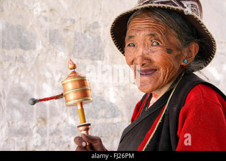 Portrait of happy woman posing with tibétain Roue de prière à Lhassa, Tibet Banque D'Images