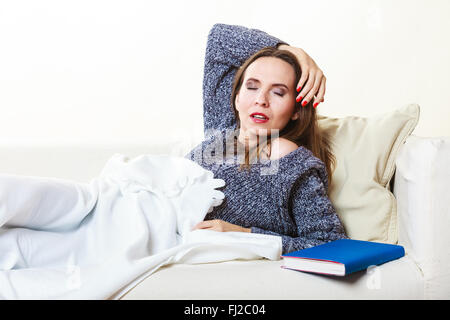 L'équilibre-santé sommeil concept. Femme endormie sur le canapé. Girl lying on couch with book détendu ou prendre power nap. Banque D'Images