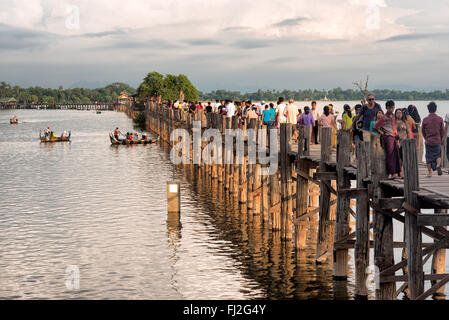 AMARAPURA, Myanmar — le pont U Bein s'étend sur le lac Taungthaman près de Mandalay. La structure en teck de 1,2 kilomètres de long, considérée comme le plus ancien et le plus long pont en teck du monde, est silhouette sur le ciel. Les piétons et les moines locaux traversent le pont pendant que les touristes observent la scène emblématique, particulièrement populaire au coucher du soleil. Banque D'Images