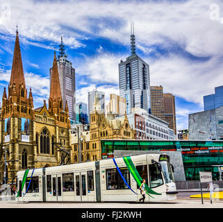 Jogging femme passé un tramway moderne blanc Melbourne et centre d'informations touristiques de Federation Square au coeur du CBD de Melbourne Australie Banque D'Images