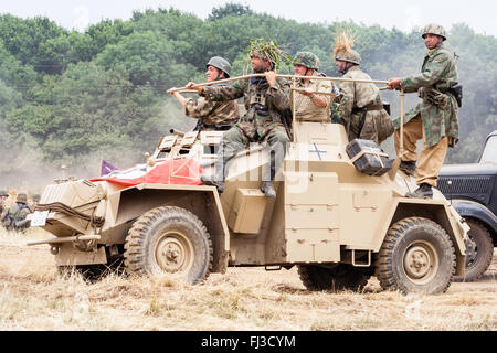 Seconde guerre mondiale re-enactment. L'Afrique allemande Korps Sdkfz 222 voiture blindée, avec le drapeau nazi sur drapé devant et soldats à cheval sur le côté, en passant par. Banque D'Images