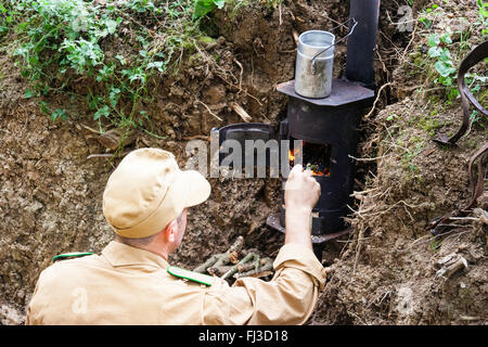 La guerre et la paix, l'Angleterre. Seconde guerre mondiale re-enactment. High angle view regardant le soldat allemand dans le domaine de l'éclairage de tranchée cuisinière Banque D'Images