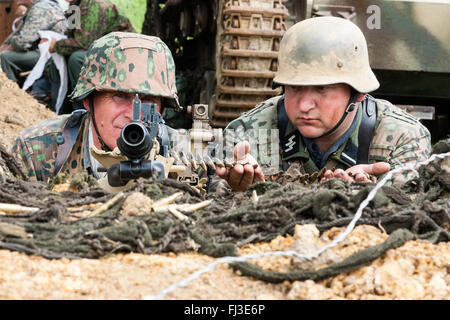 Seconde Guerre mondiale re-enactment. Deux hommes Waffen SS des uniformes de camouflage, derrière la machine gun avec bec vers au spectateur, le contact visuel. Close-up. Banque D'Images