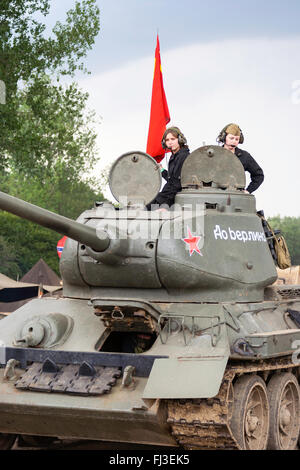 La guerre et la paix, l'Angleterre. Seconde guerre mondiale re-enactment. T34 tank russe, en face d'événements, drivern par deux adolescentes en tourelle. Red flag flying. Banque D'Images