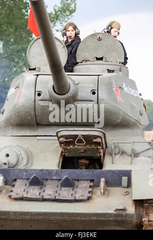 La guerre et la paix, l'Angleterre. Seconde guerre mondiale re-enactment. T34 tank russe, en face d'événements, drivern par deux adolescentes en tourelle. Red flag flying. Banque D'Images