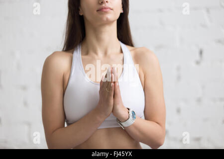 Attractive young woman working out in loft intérieur, faisant du yoga exercice avec palmiers dans Namaste, méditer, respirer, libre Banque D'Images