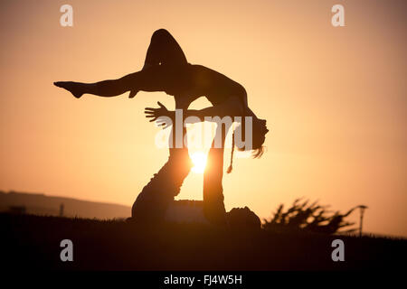 Les découpages yoga acro au coucher du soleil Banque D'Images
