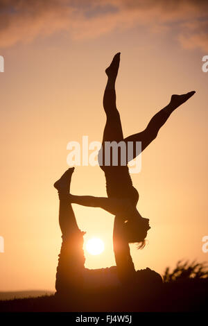 Les découpages yoga acro au coucher du soleil Banque D'Images