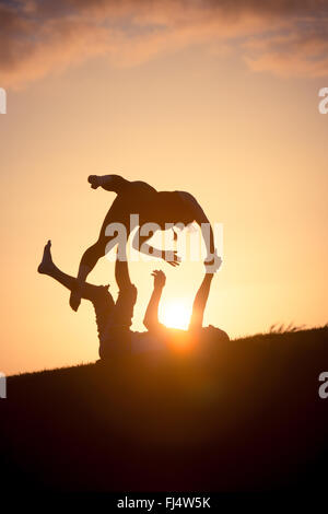Les découpages yoga acro au coucher du soleil Banque D'Images