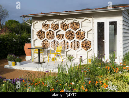 Bureau de jardin bureau d'été structures hexagonales insecte bug hôtel motel habitat terrasse en bois avec chaises de table, plantation d'abeilles, frontières de fleurs Royaume-Uni Banque D'Images