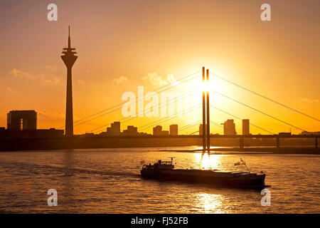 Silhouettes de navire de transport sur le Rhin avec Rheinturm et Rheinkniebruecke dans le coucher du soleil, de l'Allemagne, en Rhénanie du Nord-Westphalie, Duesseldorf Banque D'Images