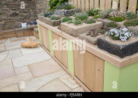 Petit jardin urbain dalles en pierre patio placards de rangement une exposition de plantes alpines dans des auges en pierre conteneurs conteneur - coin salon banc en pierre UK Banque D'Images