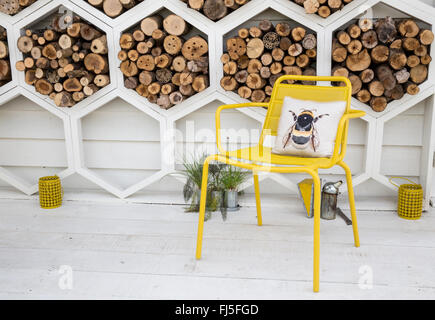 Bee Wildlife friendly chaise de jardin avec coussin d'abeille et bois de bûche stockage insectes insectes insectes hôtel motel sur terrasse peinte Royaume-Uni Banque D'Images