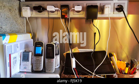 Un grand nombre de câbles de recharge pour téléphones portables, téléphones mobiles, tablettes d'anf alarme bébé dans un plugbar Banque D'Images