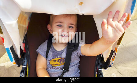 Heureux petit garçon assis dans une poussette et en agitant, portrait d'un enfant, Pays-Bas Banque D'Images