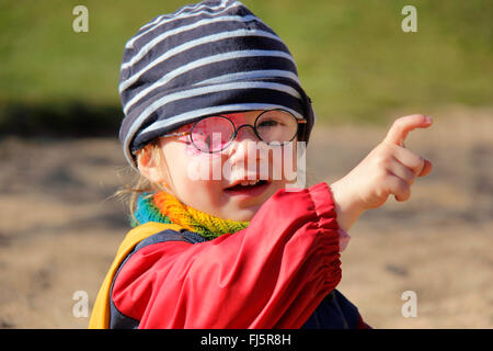 Petite fille avec des lunettes et un pansement oculaire pointant du doigt quelque chose, Allemagne Banque D'Images