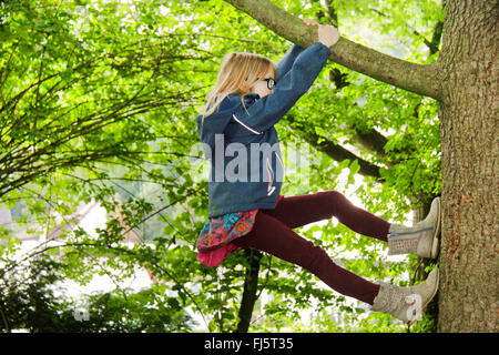 Bold fille grimper sur un arbre, Allemagne Banque D'Images