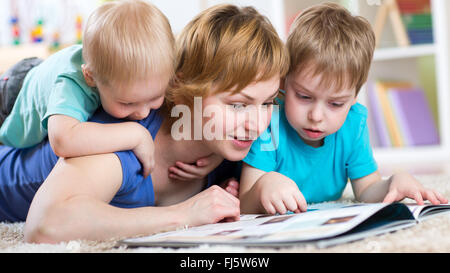 Famille heureuse s'allonger sur le sol et la lecture d'un livre Banque D'Images
