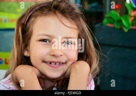 Fille de bonne humeur resting head on hands, portrait d'un enfant, Allemagne Banque D'Images