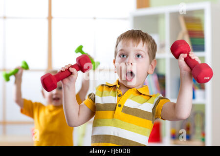 Drôle enfants garçons l'entraînement avec haltères à la maison. Vie saine, sportive des enfants. Banque D'Images