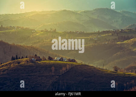 Paysage rural avec la lumière du soleil tôt le matin sur les collines et vallées de Bran-Rucar Sirnea, village, Brasov, Roumanie. Banque D'Images