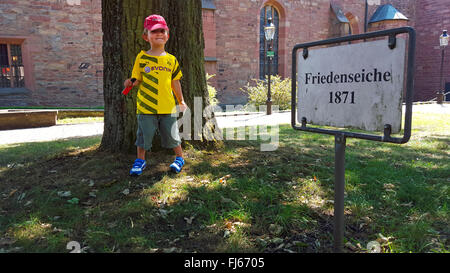 Chêne (Quercus spec.), enfant de football shirt debout devant des monument naturel chêne la paix de 1871, l'Allemagne, Bade-Wurtemberg, Buchenberg Banque D'Images