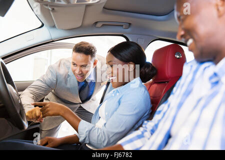 Vendeur montrant nouvelle voiture à African couple in showroom Banque D'Images