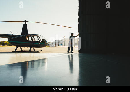 Ouverture mécanique la porte d'un hangar d'avion à l'aide d'un hélicoptère Banque D'Images