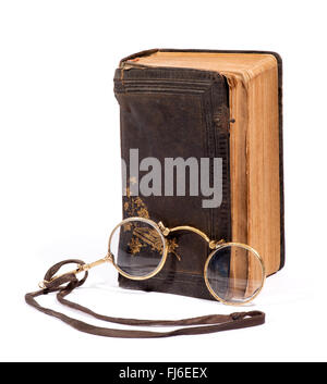 Vintage paire de lunettes pince-nez sur une lanière pour la lecture avec un vieux livre relié de cuir en détresse usés Banque D'Images