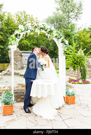 Premier baiser des nouveaux mariés en vertu de l'arche de mariage Banque D'Images