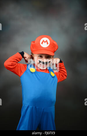 Garçon habillé en Super Mario Bros contre fond gris. Banque D'Images