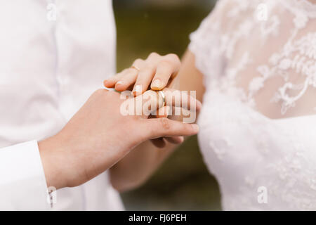 Mariée porte un anneau de mariage sur le marié Banque D'Images