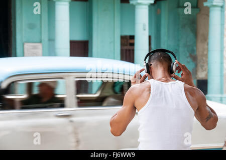 Garçon d'écouter de la musique avec un casque dans la rue - La Havane, Cuba Banque D'Images