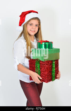 Adorable jeune fille portant un chapeau de Noël et holding gifts, contre l'arrière-plan blanc. Banque D'Images