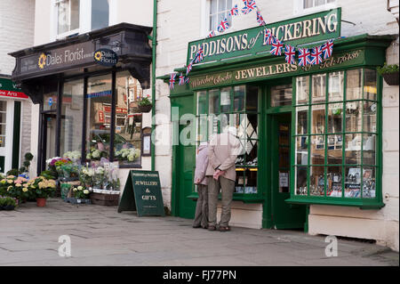 D'âge mûr regarde dans une vitrine Boutique des Joailliers (C19e, attrayant et pittoresque façade) - Place du marché, Pickering, North Yorkshire, Angleterre, Royaume-Uni. Banque D'Images