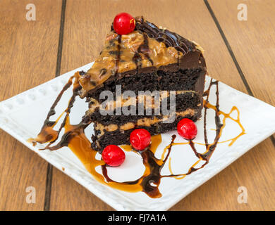 Délicieux gâteau chocolat caramel aux amandes et cerises rouges Banque D'Images