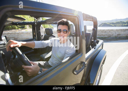 Les jeunes Chinois heureux homme conduisant une jeep Banque D'Images