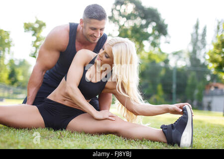 Jeune couple l'exercice et les étirements muscles avant l'activité sportive - piscine dans la nature Banque D'Images