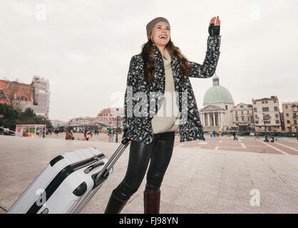 Services et de la fièvre. Pack un sac et nous allons rencontrer à la gare Santa Lucia de Venise, Italie. Souriante jeune femme avec gros bagages sac Banque D'Images