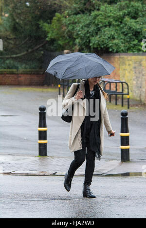 Girl with umbrella crossing Road dans la pluie Banque D'Images