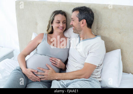 Expecting couple lying on bed and chatting Banque D'Images