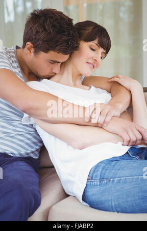 Jeune couple de câlins sur canapé Banque D'Images