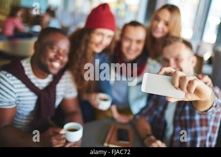 Guy avec smartphone faisant des selfies lui et ses amis Banque D'Images