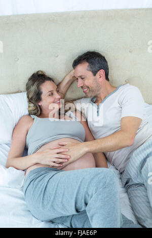 Expecting couple lying on bed and chatting Banque D'Images