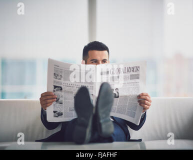 Contemporary businessman reading newspaper in office Banque D'Images