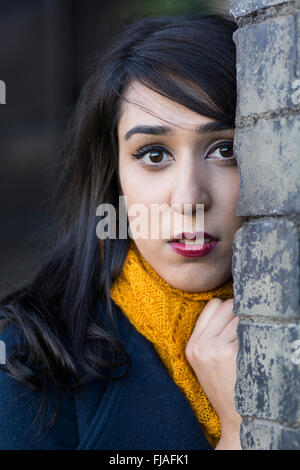 Jeune femme debout derrière un mur à l'extérieur Banque D'Images
