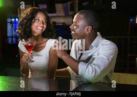 Couple talking et souriant tout en ayant des boissons au comptoir du bar Banque D'Images