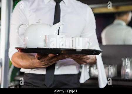 Mid section of waiter serving plateau Banque D'Images