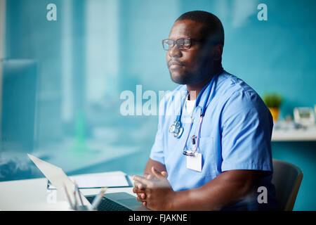 Un médecin travaillant avec sérieux à la table pour ordinateur portable Banque D'Images