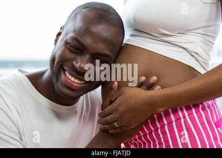 L'homme à l'écoute de l'estomac de femme enceinte Banque D'Images